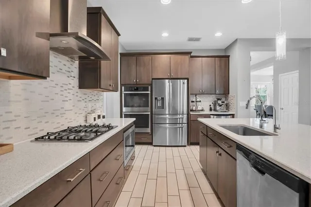 a kitchen with stainless steel appliances a sink a stove a refrigerator cabinets and a counter top space