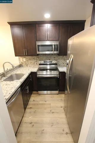 a kitchen with granite countertop wooden cabinets and stainless steel appliances