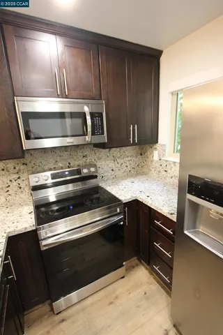 a kitchen with granite countertop a sink stainless steel appliances and cabinets