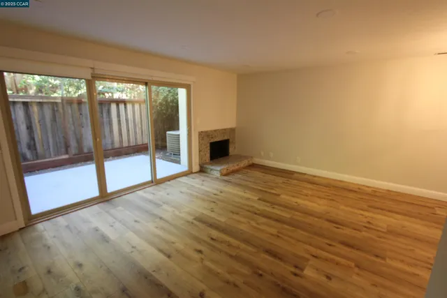 a view of empty room with wooden floor and fireplace