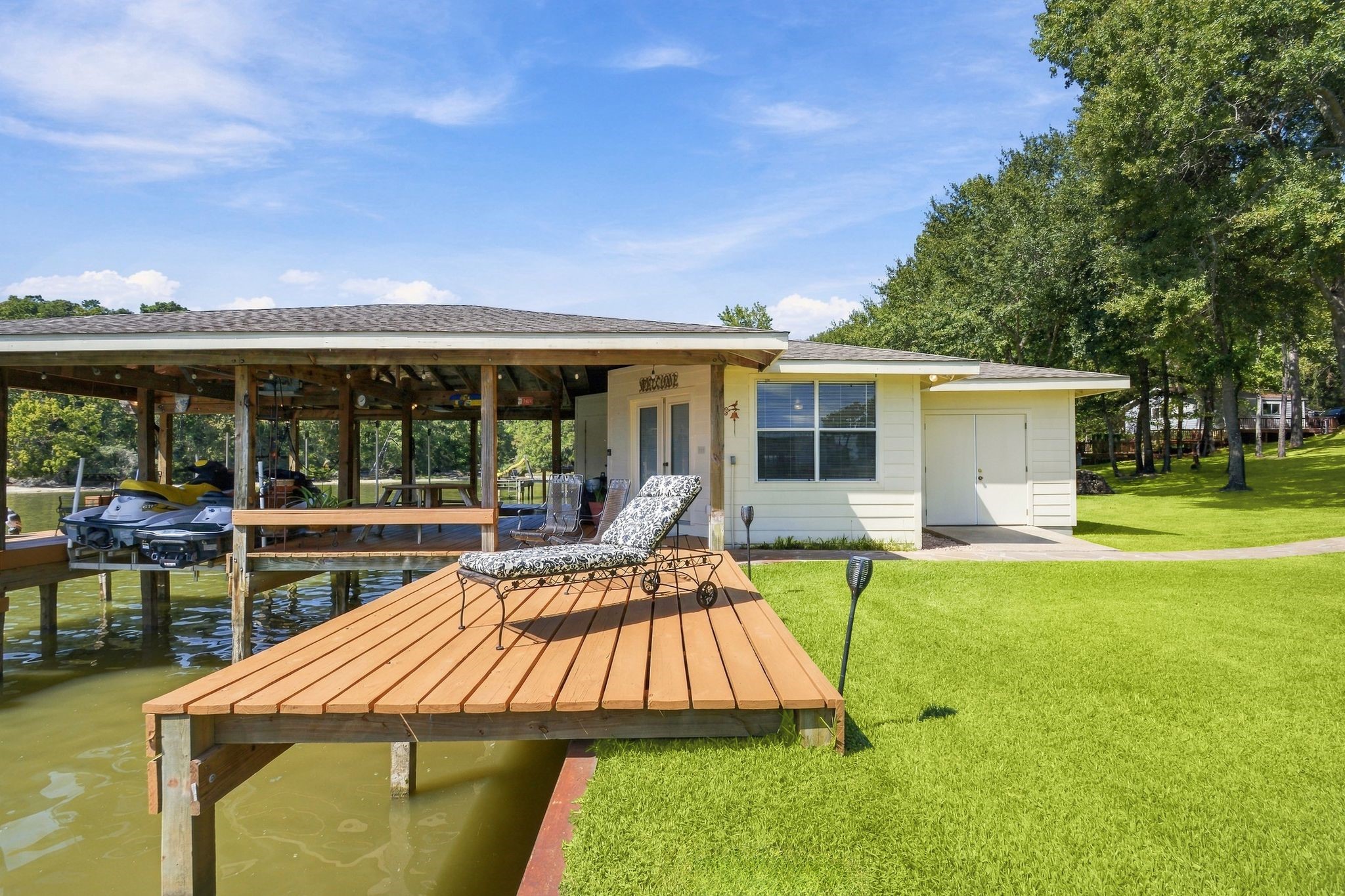 20341 Bay Hill Road Point Blank, TX 77364 - Photo 40 of 50 Peaceful lakeside retreat featuring a spacious deck with a sun lounger, perfect for relaxation and enjoying serene water views.