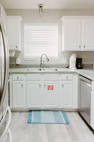 a kitchen with granite countertop white cabinets sink and white appliances