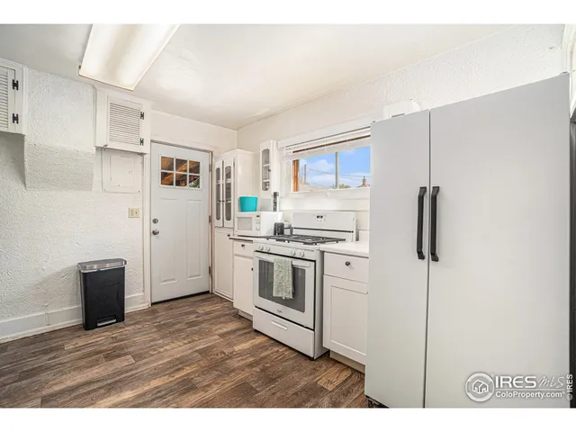 a kitchen with stainless steel appliances white cabinets and wooden floor