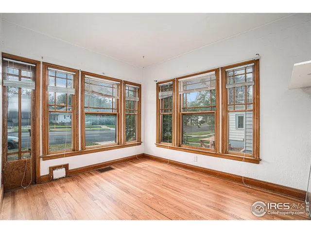 a view of an empty room with wooden floor and windows