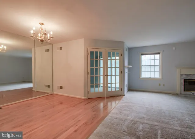 an empty room with chandelier fan and windows