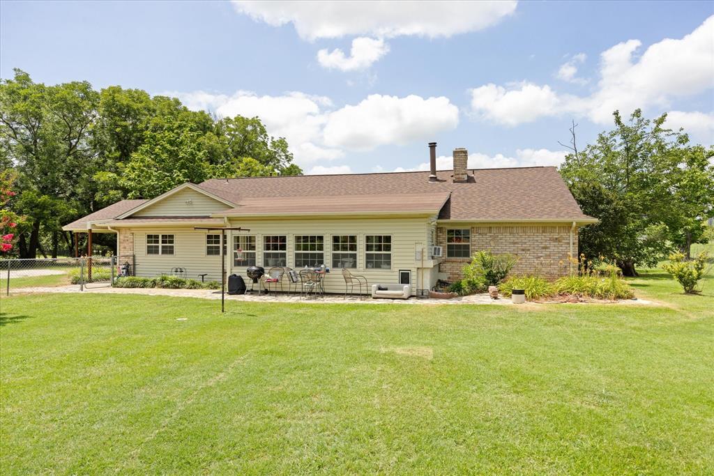 4210 Waples Road Granbury, TX 76049 - Photo 3 of 37 Expansive green lawn bordering a brick and siding exterior with a sunroom addition