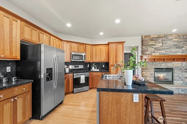 a kitchen with stainless steel appliances granite countertop a refrigerator a stove top oven a sink and dishwasher