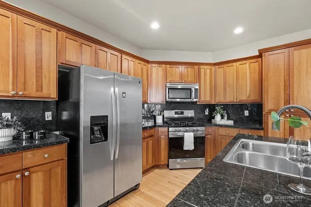a kitchen with stainless steel appliances granite countertop a refrigerator a stove top oven a sink and dishwasher