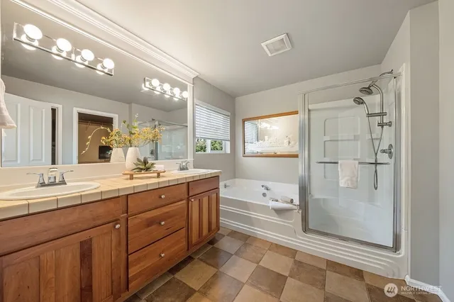 a spacious bathroom with a tub sink shower and mirror