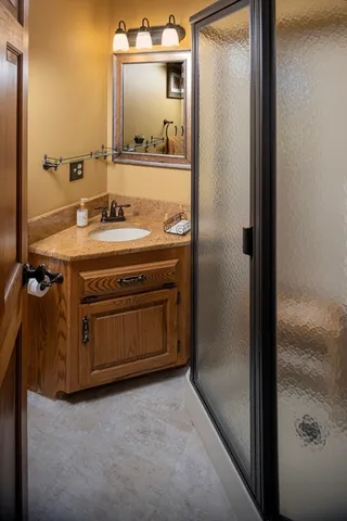 a bathroom with a granite countertop sink a mirror and a shower