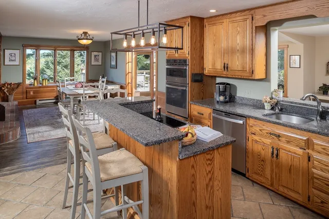 a kitchen with stainless steel appliances granite countertop a stove a sink dishwasher and a refrigerator with wooden cabinets
