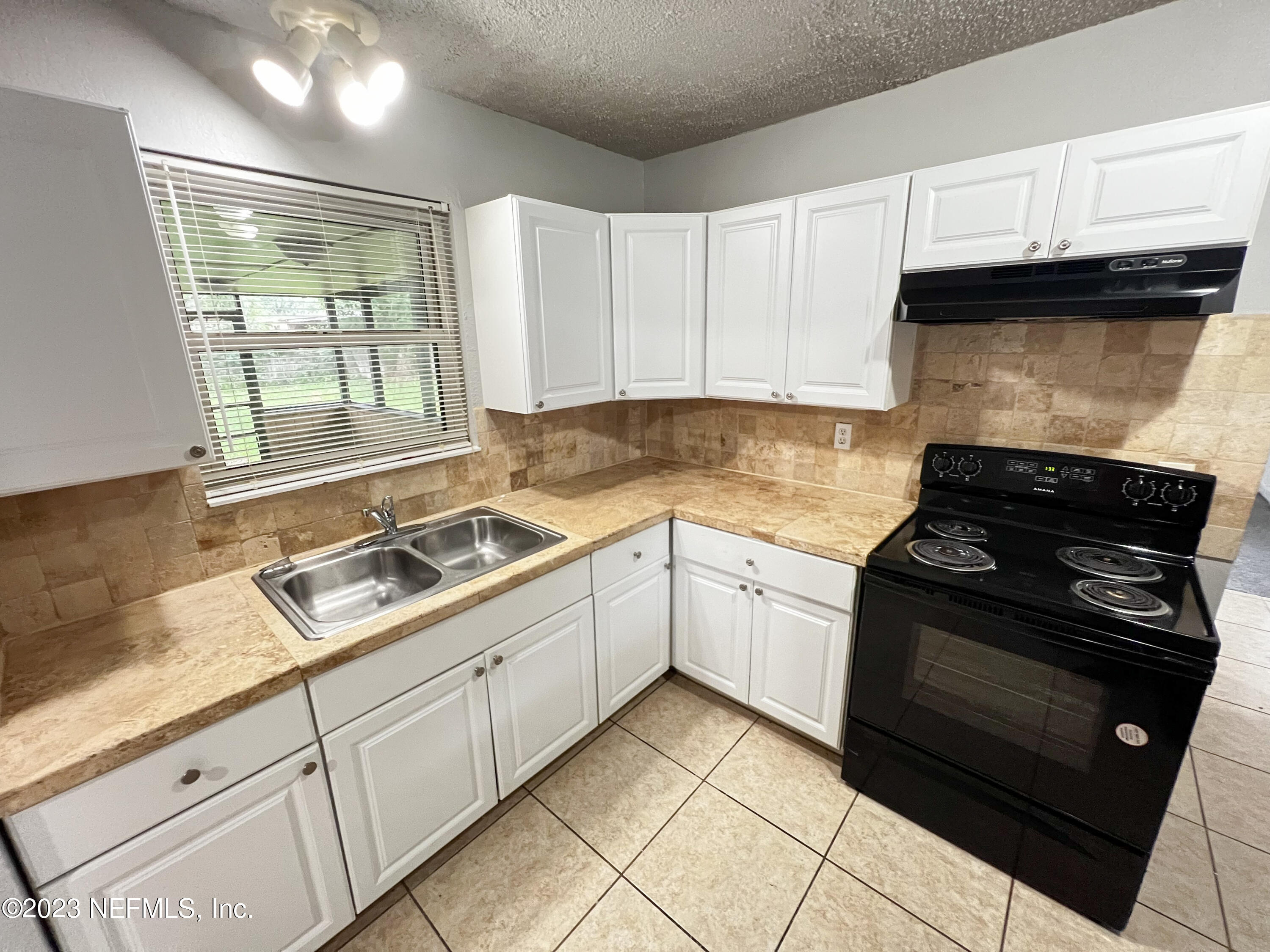 7025 Rollo Road Jacksonville, FL 32205 - Photo 9 of 37 a kitchen with granite countertop cabinets and steel stainless steel appliances