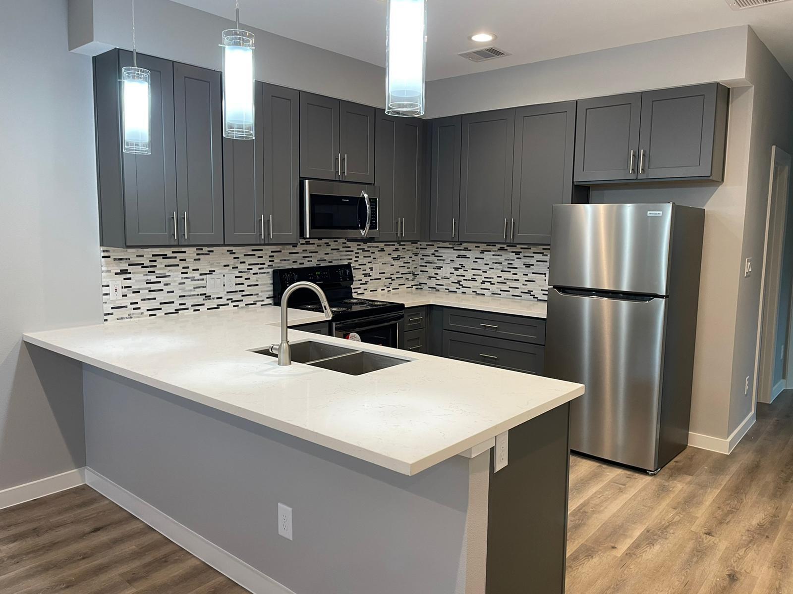 9114 Caddo Road, Unit A & B Houston, TX 77078 - Photo 2 of 24 Modern kitchen featuring grey shaker-style cabinetry, stainless steel appliances, a mosaic tile backsplash, and light-toned countertops