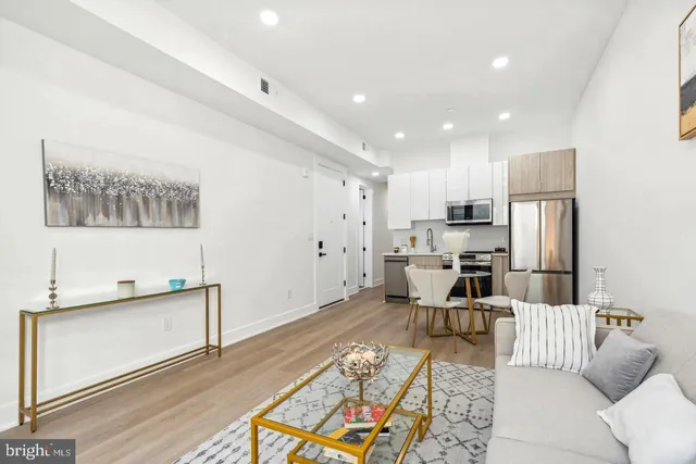 a living room with stainless steel appliances furniture and a kitchen view
