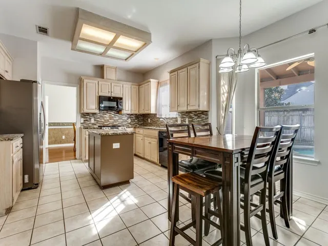 a kitchen with stainless steel appliances granite countertop a stove a sink dishwasher a dining table and chairs with wooden floor