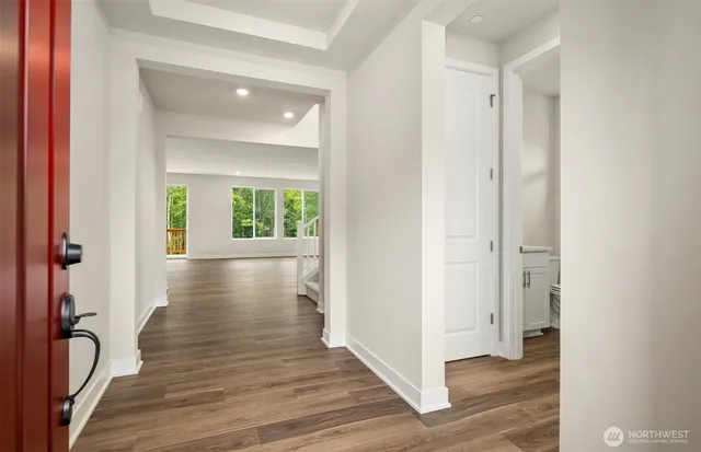 a view of a hallway with wooden floor and a bathroom