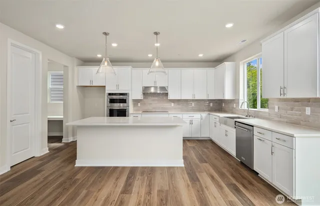 a large kitchen with cabinets wooden floor and stainless steel appliances
