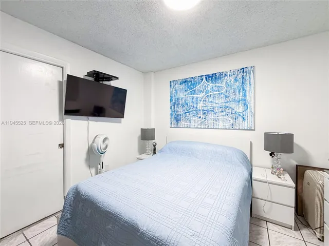 a bedroom with a bed and a flat tv screen on the dresser