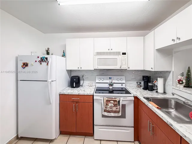 a kitchen with a white refrigerator a sink a stove and white cabinets