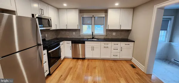 a kitchen with granite countertop a refrigerator stove and wooden floor