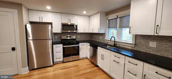 a kitchen with stainless steel appliances granite countertop a refrigerator a sink a stove a microwave and cabinets