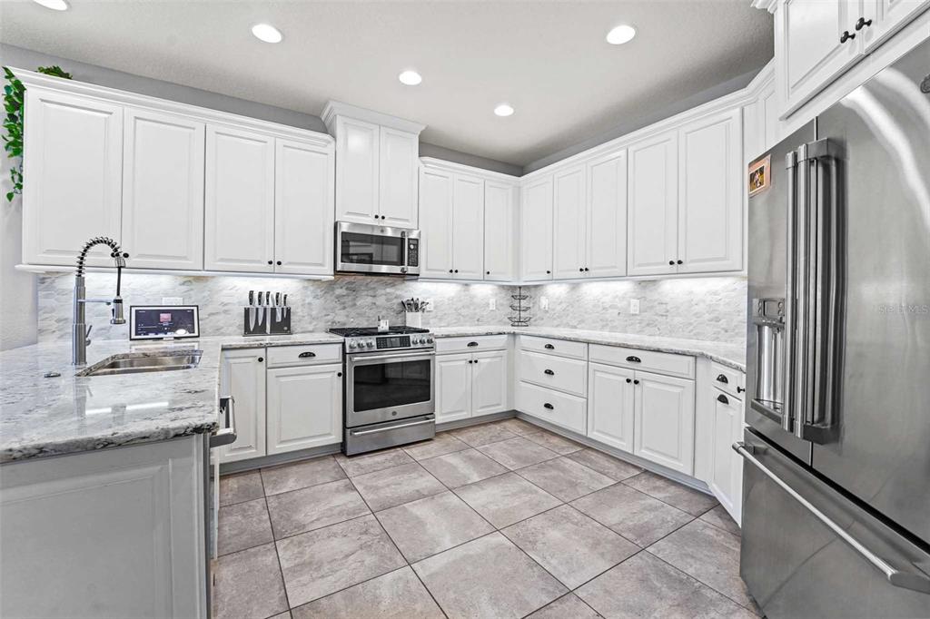 8903 Arabella Lane Seminole, FL 33777 - Photo 8 of 47 a kitchen with granite countertop white cabinets and stainless steel appliances