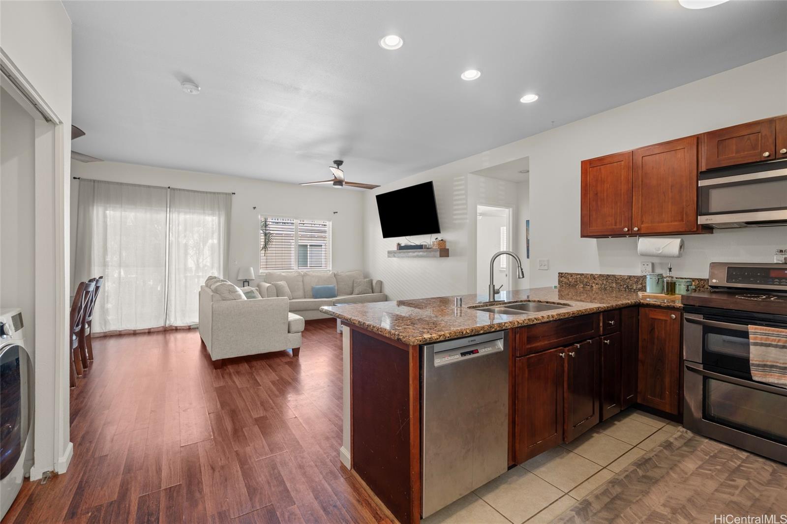 a kitchen with stainless steel appliances granite countertop a stove top oven a sink dishwasher and a microwave oven with wooden floor