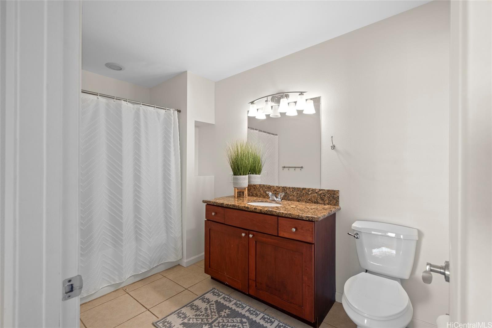 87-176 Maipalaoa Road, Unit D12 Waianae, HI 96792 - Photo 11 of 25 a bathroom with a granite countertop toilet sink and mirror