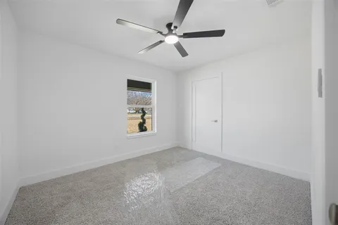 an empty room with windows and fan