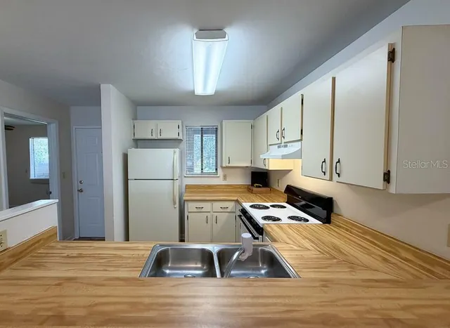a kitchen with a refrigerator sink and cabinets