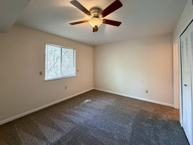 an empty room with windows and fan