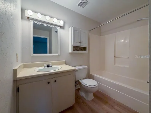 a bathroom with a sink a toilet a mirror a vanity and shower