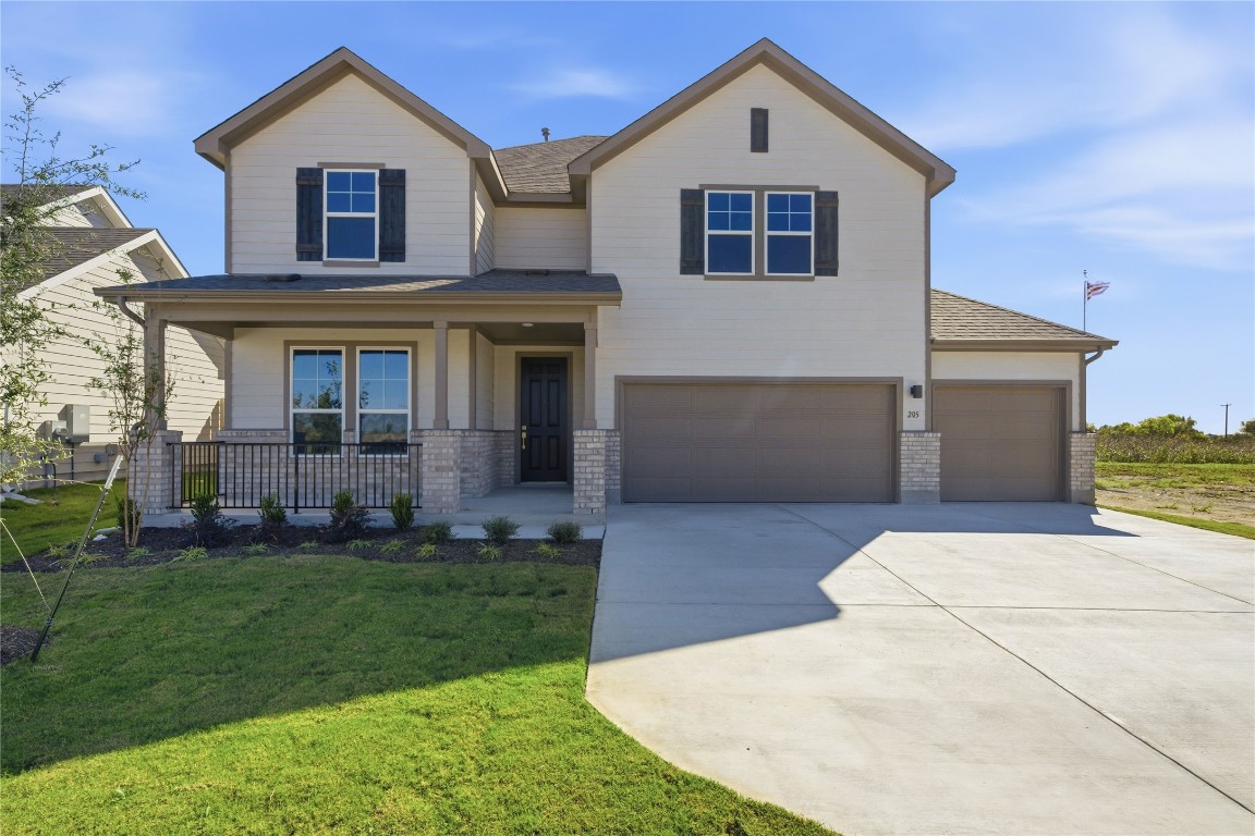 View of front of home featuring brick siding, a porch, driveway, a garage, and a front lawn