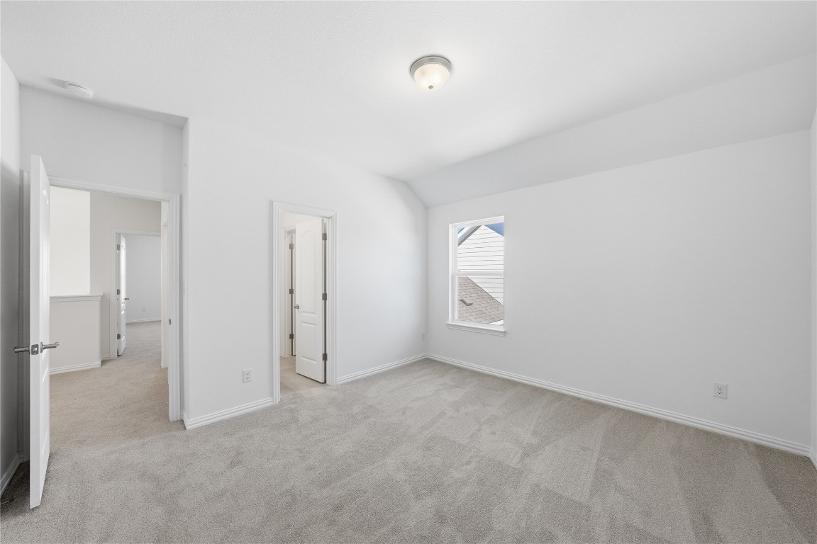 205 Caraway Drive Taylor, TX 76574 - Photo 12 of 15 Unfurnished bedroom featuring light carpet and vaulted ceiling