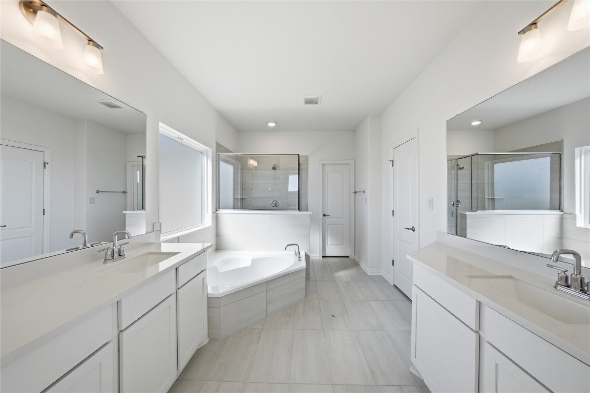 205 Caraway Drive Taylor, TX 76574 - Photo 9 of 15 Bathroom with a bath, two vanities, light tile patterned flooring, and a stall shower
