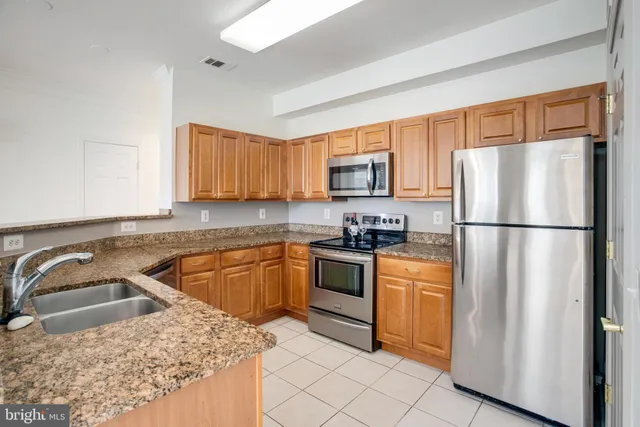 a kitchen with stainless steel appliances granite countertop a refrigerator sink stove microwave and cabinets