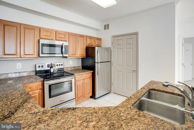 a kitchen with granite countertop a sink stove and refrigerator