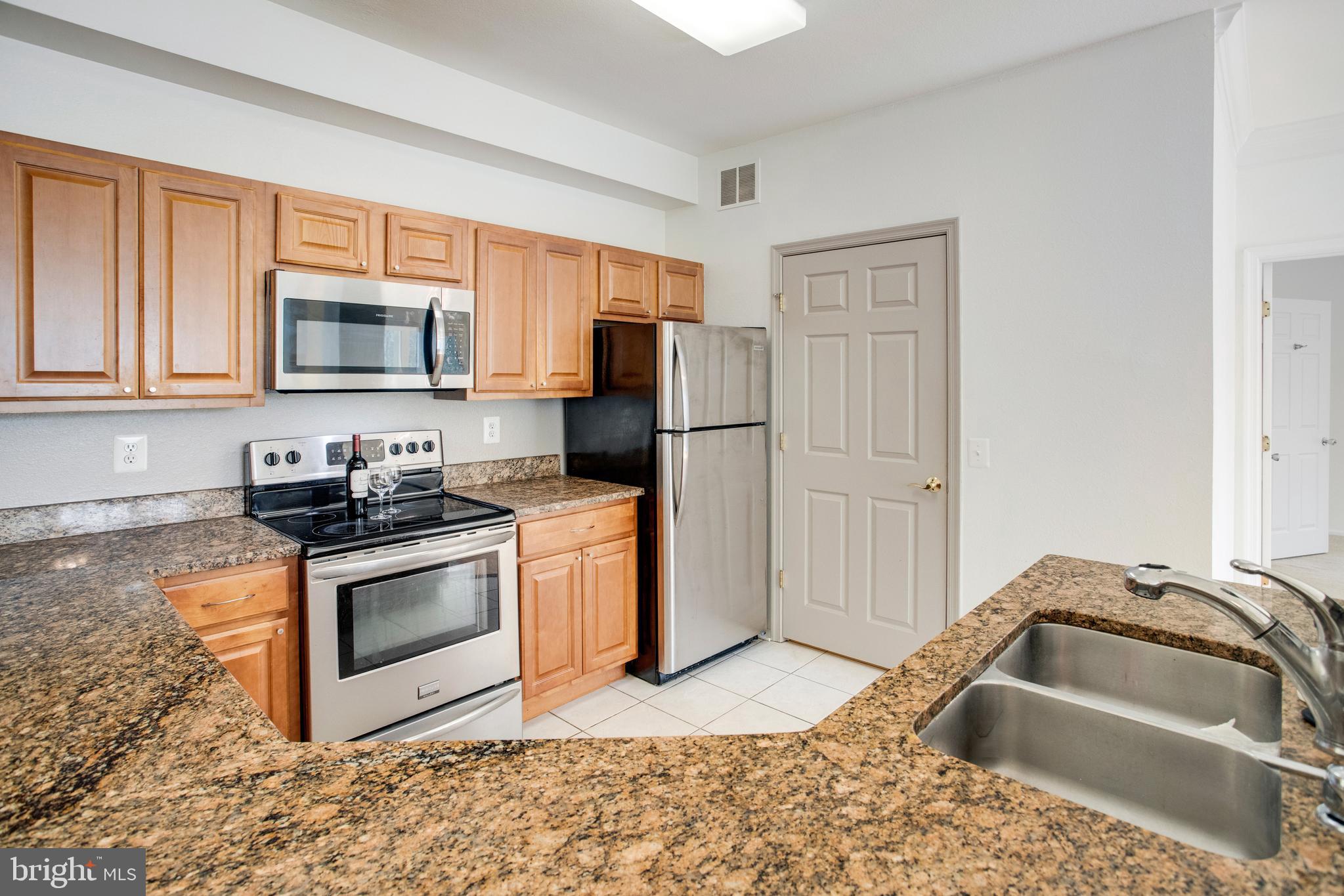 1530 Spring Gate Dr., Unit 9308 McLean, VA 22102 - Photo 12 of 38 a kitchen with granite countertop a sink stove and refrigerator