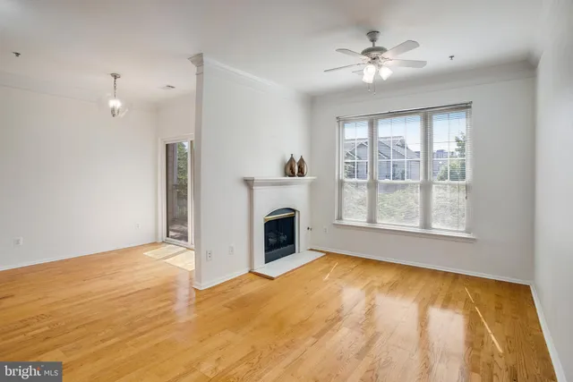 a view of a livingroom with a fireplace a ceiling fan and windows