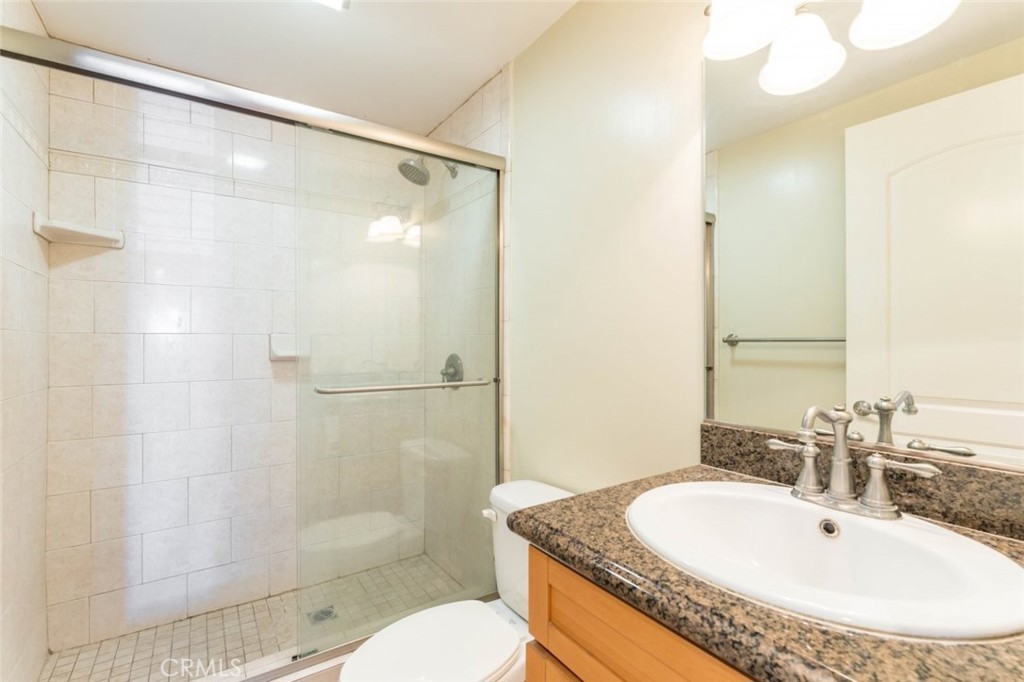 511 East Harvard Road, Unit 101 Burbank, CA 91501 - Photo 16 of 29 a bathroom with a granite countertop sink a toilet a mirror and shower