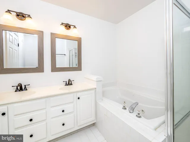 a bathroom with a tub a sink and mirror