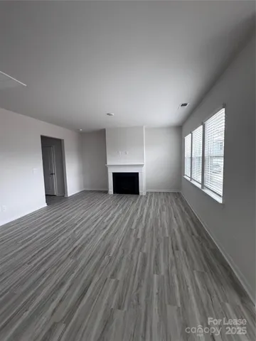 a view of empty room with wooden floor and fireplace