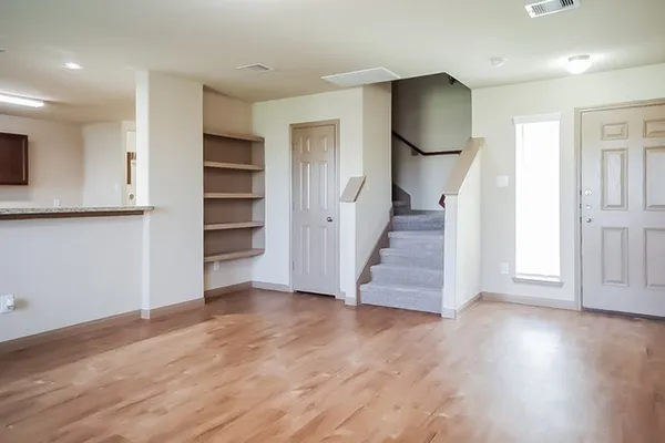 an empty room with wooden floor and staircase