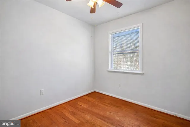 an empty room with chandelier fan and windows
