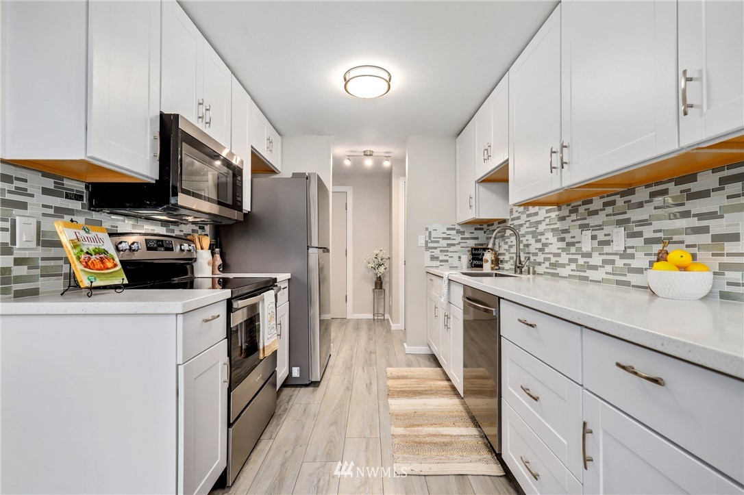 7001 Sand Point Way Northeast, Unit C309 Seattle, WA 98115 - Photo 5 of 38 a kitchen with stainless steel appliances a stove refrigerator sink and microwave