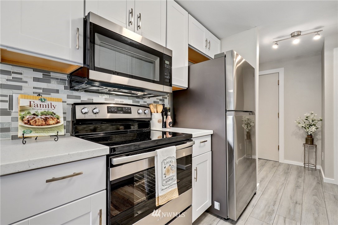 7001 Sand Point Way Northeast, Unit C309 Seattle, WA 98115 - Photo 7 of 38 a kitchen with stainless steel appliances granite countertop a stove and a microwave