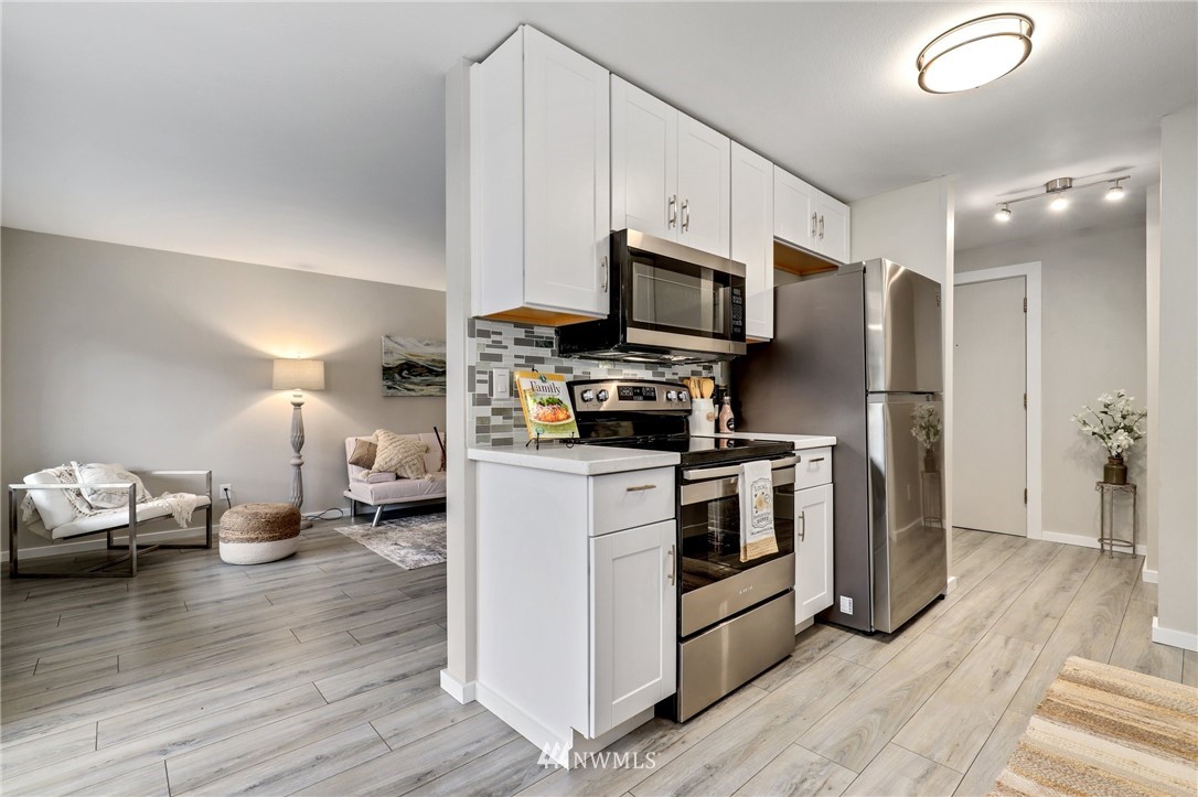 7001 Sand Point Way Northeast, Unit C309 Seattle, WA 98115 - Photo 8 of 38 a kitchen with stainless steel appliances a stove a refrigerator a sink and white cabinets