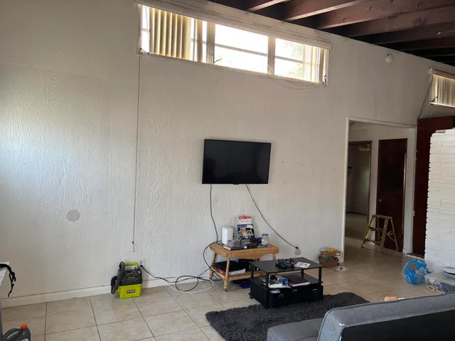 a living room with furniture a flat screen tv and a window