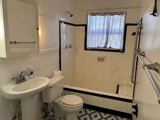 a bathroom with a sink a toilet a mirror and shower