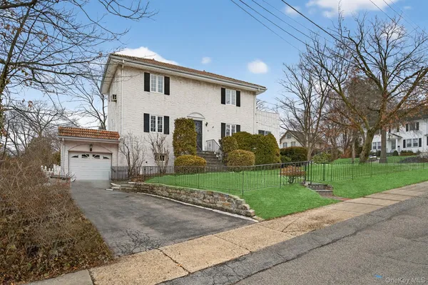 a view of a white house next to a yard and large trees
